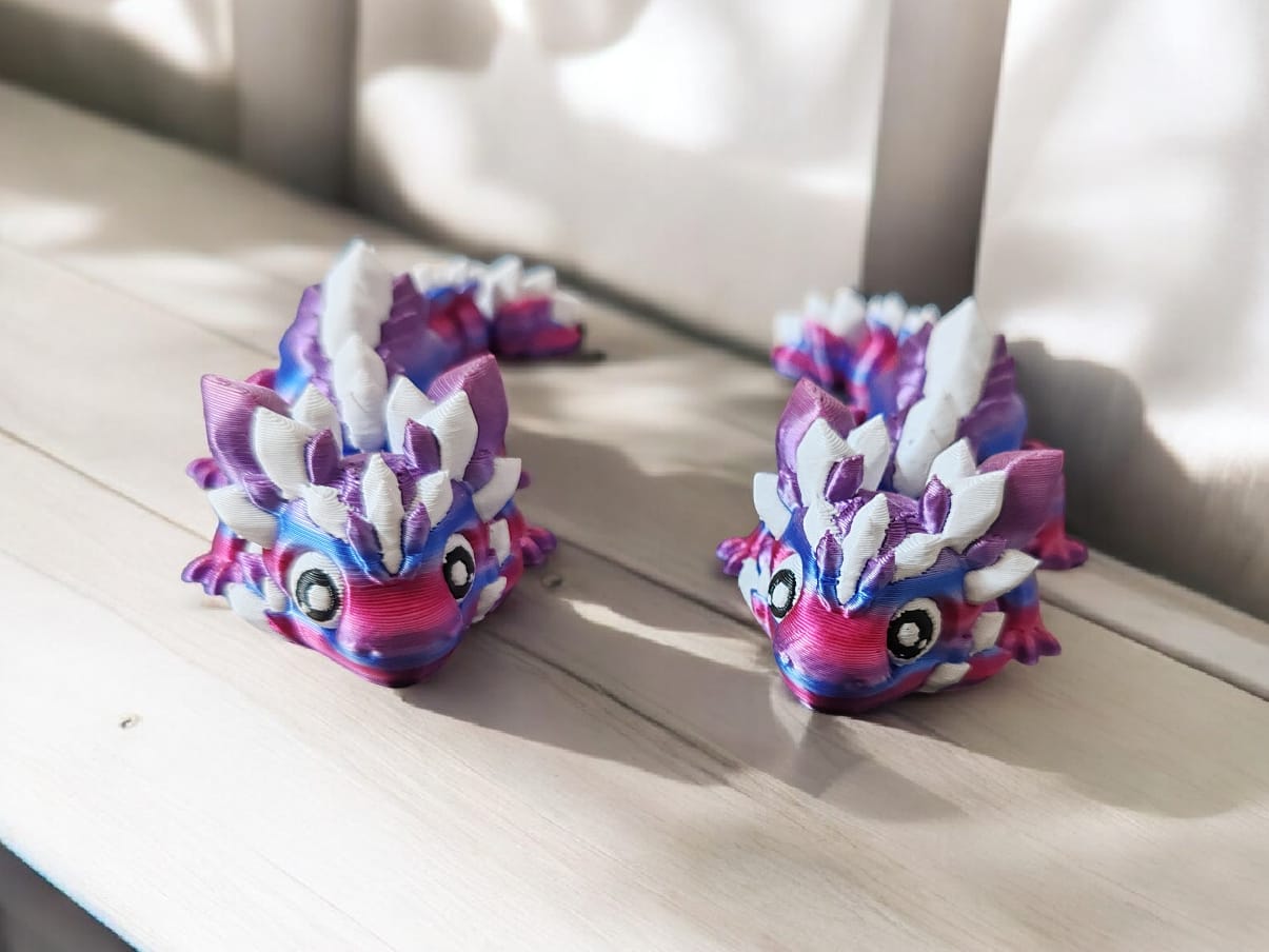 Two colorful dragon-shaped toys on a wooden surface with a blurred background