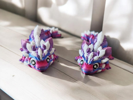 Two colorful dragon-shaped toys on a wooden surface with a blurred background