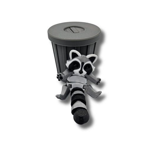 Gray and black articulated raccoon figurine in trash can