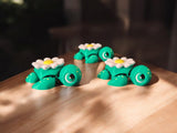 Three daisy flower themed articulated turtles with white and yellow petals